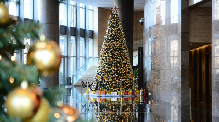 Minh họa cây thông Noel trang trí quả châu dày đặc kèm hàng rào cột chắn phân luồng tại sảnh tòa nhà văn phòng